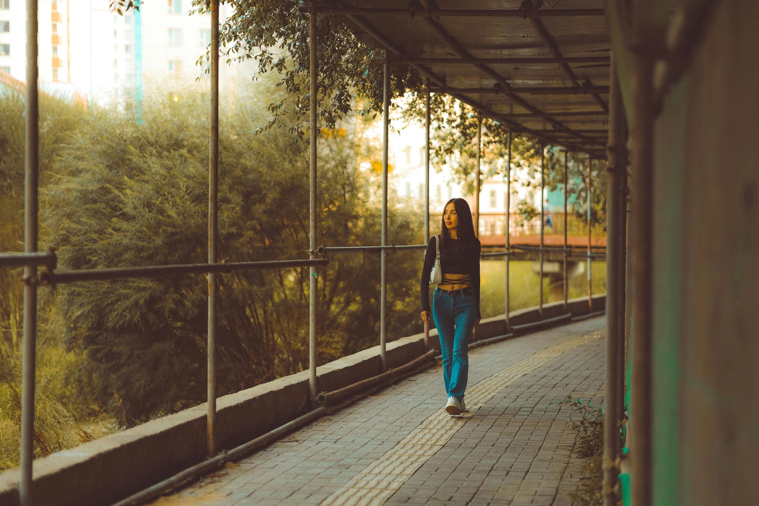 Woman walking through bridge with green foliage